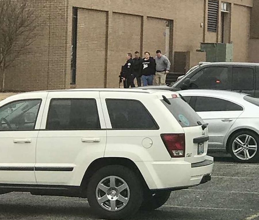 UPDATES TO REMOVE NUMBER OF PEOPLE INJURED - Police escort a person, second from right, out of the Marshall County High School after shooting there, Tuesday, Jan 23, 2018, in Benton, Ky.  Gov. Matt Bevin said two people were killed numerous others were injured in the shooting. (Dominico Caporali via AP)