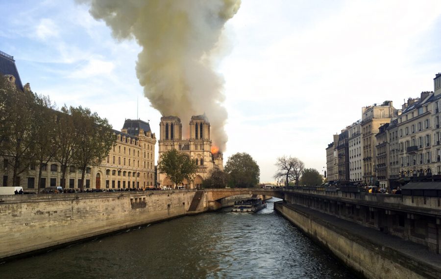 Notre Dame cathedral is burning in Paris, Monday, April 15, 2019. Massive plumes of yellow brown smoke is filling the air above Notre Dame Cathedral and ash is falling on tourists and others around the island that marks the center of Paris. (AP Photo/Lori Hinnant)
