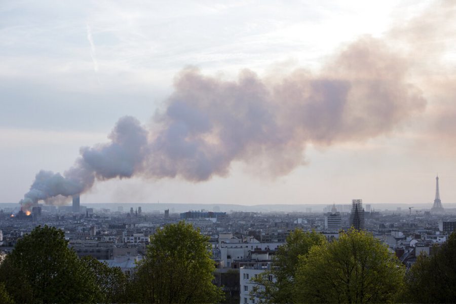 Smoke fill the air as Notre Dame cathedral is burning in Paris, Monday, April 15, 2019. Massive plumes of yellow brown smoke is filling the air above Notre Dame Cathedral and ash is falling on tourists and others around the island that marks the center of Paris. (AP Photo/Rafael Yaghobzadeh)