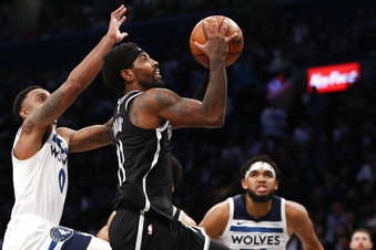 Minnesota Timberwolves guard Jeff Teague (0) defends against Brooklyn Nets guard Kyrie Irving (11) as Irving goes up for a shot in overtime of an NBA basketball game Wednesday, Oct. 23, 2019, in New York. Timberwolves Karl Anthony-Towns is at right. Irving had 50 points but the Timberwolves won 127-126. (AP Photo/Kathy Willens)