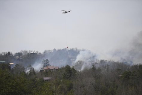 A helicopter dumps water onto a wildfire Wednesday, March 30, 2022, in Sevierville, Tenn. Firefighters sought to get a handle Wednesday on a wildfire spreading near Great Smoky Mountains National Park in Tennessee, amid mandatory evacuations as winds whipped up ahead of a line of strong storms forecast to move in overnight.(Caitie McMekin/Knoxville News Sentinel via AP)