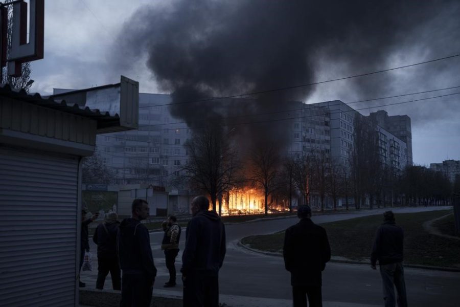 Residents stand outside their apartments as shops burn after a Russian attack in Kharkiv, Ukraine, Monday, April 11, 2022. 