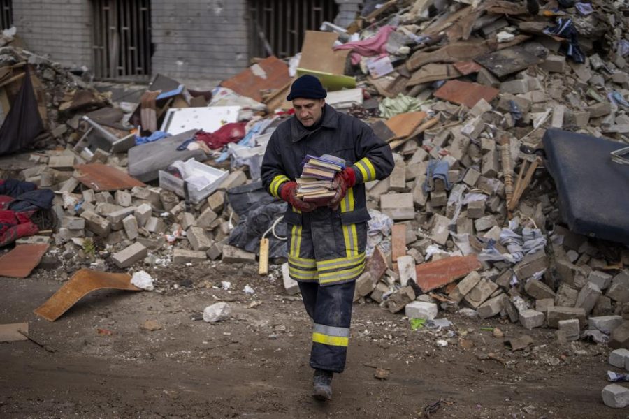 A firefighter carries books away from the remains of a house following a Russian attack in Chernihiv, Ukraine, Friday, April 22, 2022. (AP Photo/Emilio Morenatti)
