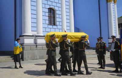 Soldiers carry a coffin with remains of a volunteer soldier Oleksandr Makhov, a well-known Ukrainian journalist,
killed by the Russian troops, at St Michael cathedral in Kyiv, Ukraine, Monday, May 9, 2022. The coffin is followed
by Makhovs widow.(AP Photo/Efrem Lukatsky)
