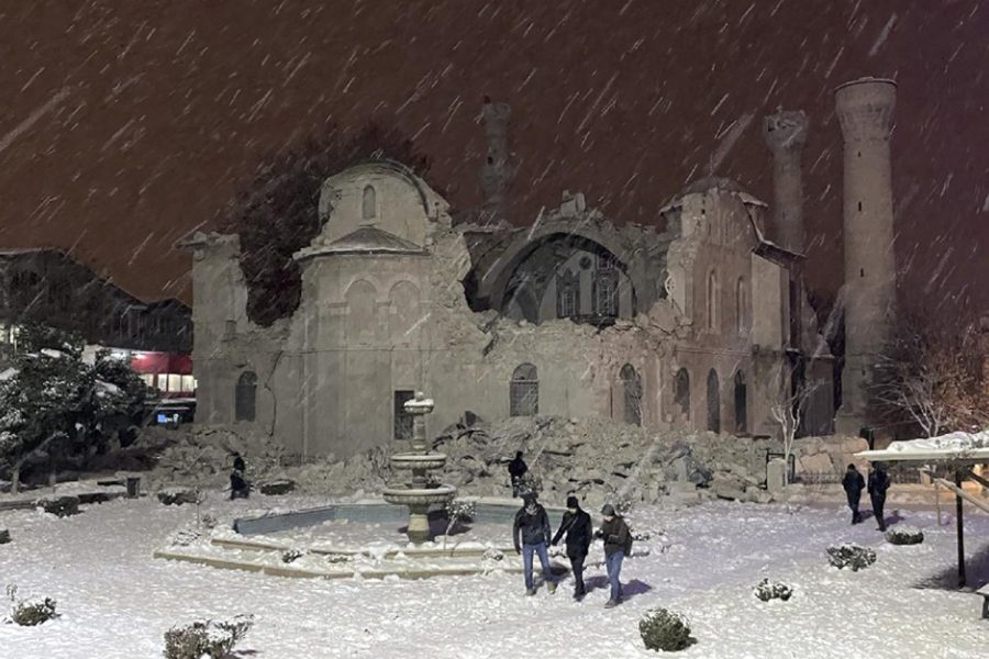 People walk next to a mosque destroyed by an earthquake in Malatya, Turkey, Monday, Feb. 6, 2023. A powerful quake has knocked down multiple buildings in southeast Turkey and Syria and many casualties are feared. (DIA images via AP)
